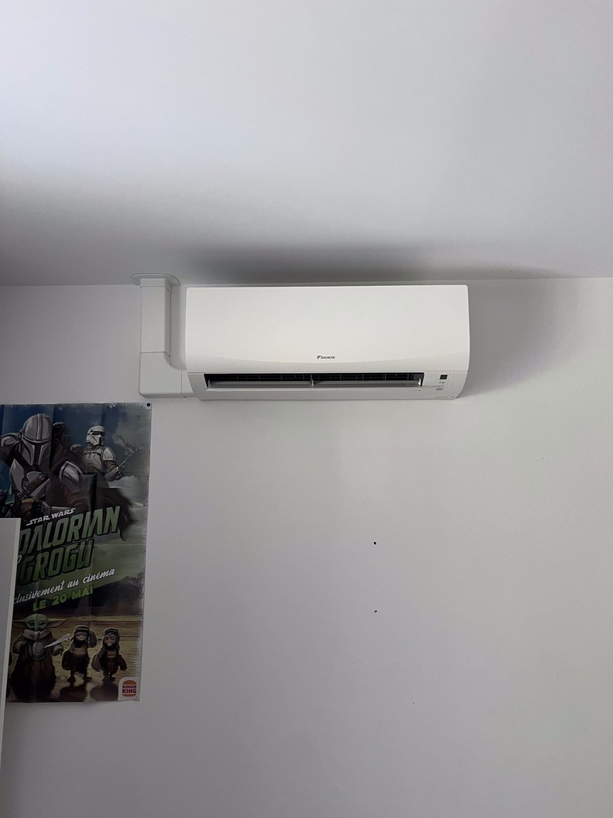 Unité intérieure Daikin installée en hauteur dans une chambre d'enfant, goulotte alignée sur l'angle du mur