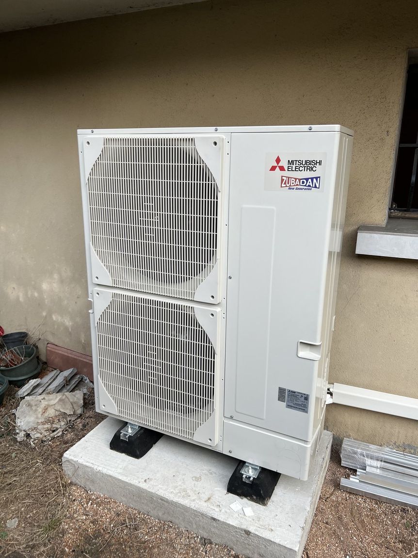 Groupe extérieur Mitsubishi Electric sur plots, posé sur une dalle béton en pied de façade