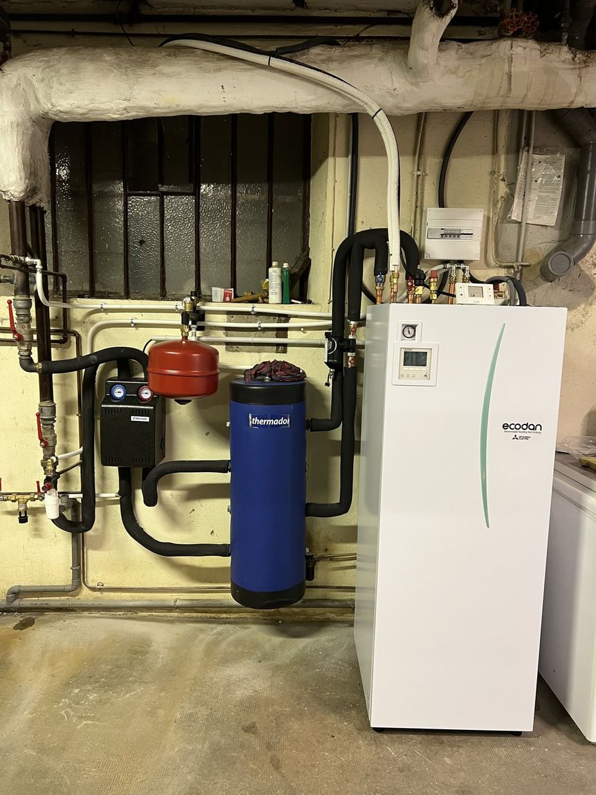Module Ecodan installé dans une cave, ballon tampon bleu Thermador et vase d'expansion rouge
